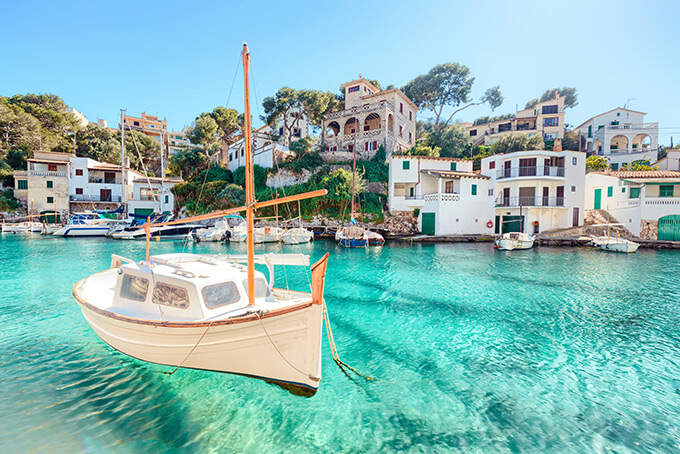 Bootje in helderblauw water met een dorpje op de achtergrond