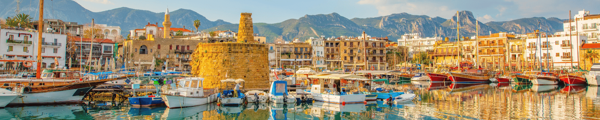 Stadje op Cyprus vanaf het water, met bootjes in de haven en oude gebouwen langs de kade