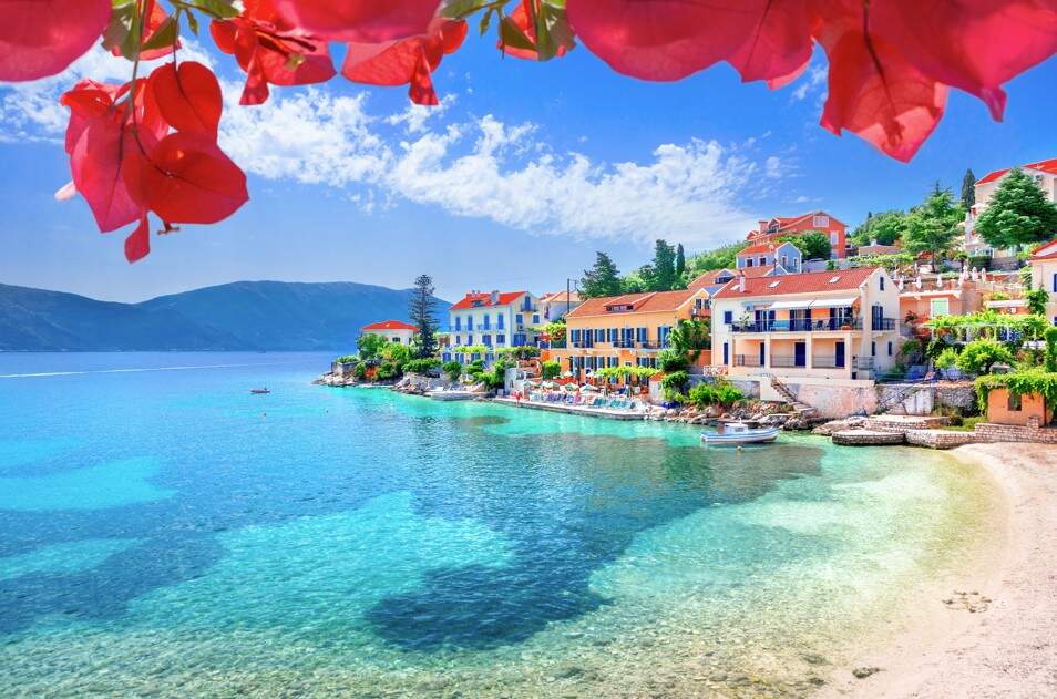 Doorkijkje door roze bloemen op de gekleurde huisjes aan zee op Kefalonia
