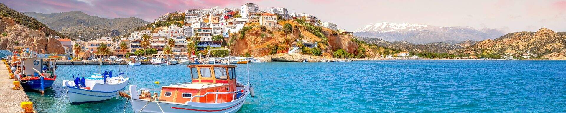 Haven op Kreta met bootjes en een bergachtig landschap op de achtergrond