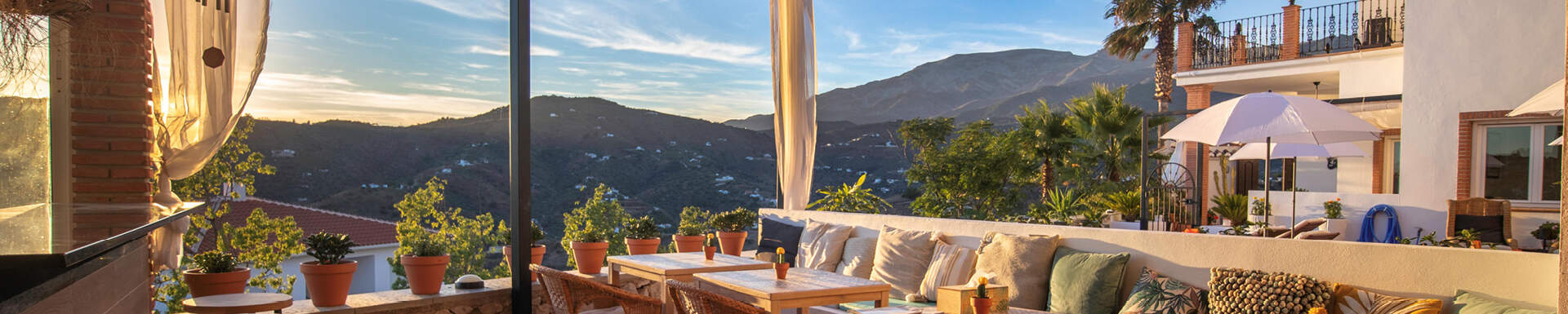 uitzicht vanaf terras met banken en kussentjes over bergtoppen tijdens zonsondergang