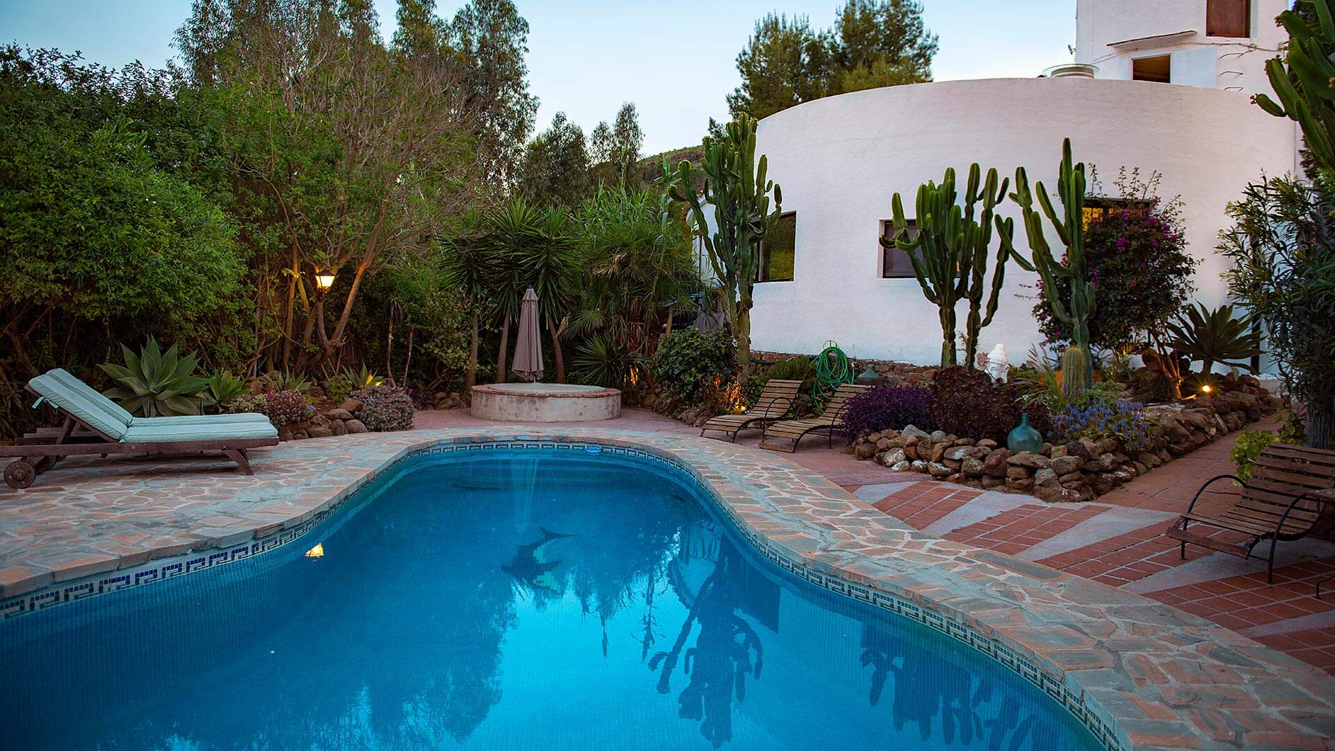 wit vakantiehuis met villa en ligbedjes omgeven door groen