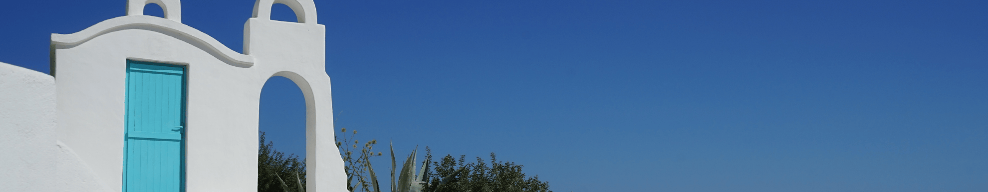 Strakblauwe lucht met op de voorgrond een wit kerkje