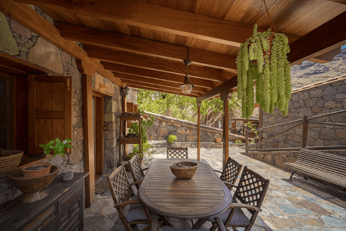 Grote tafel met stoelen onder een houten dak, op het terras van een knus hotel